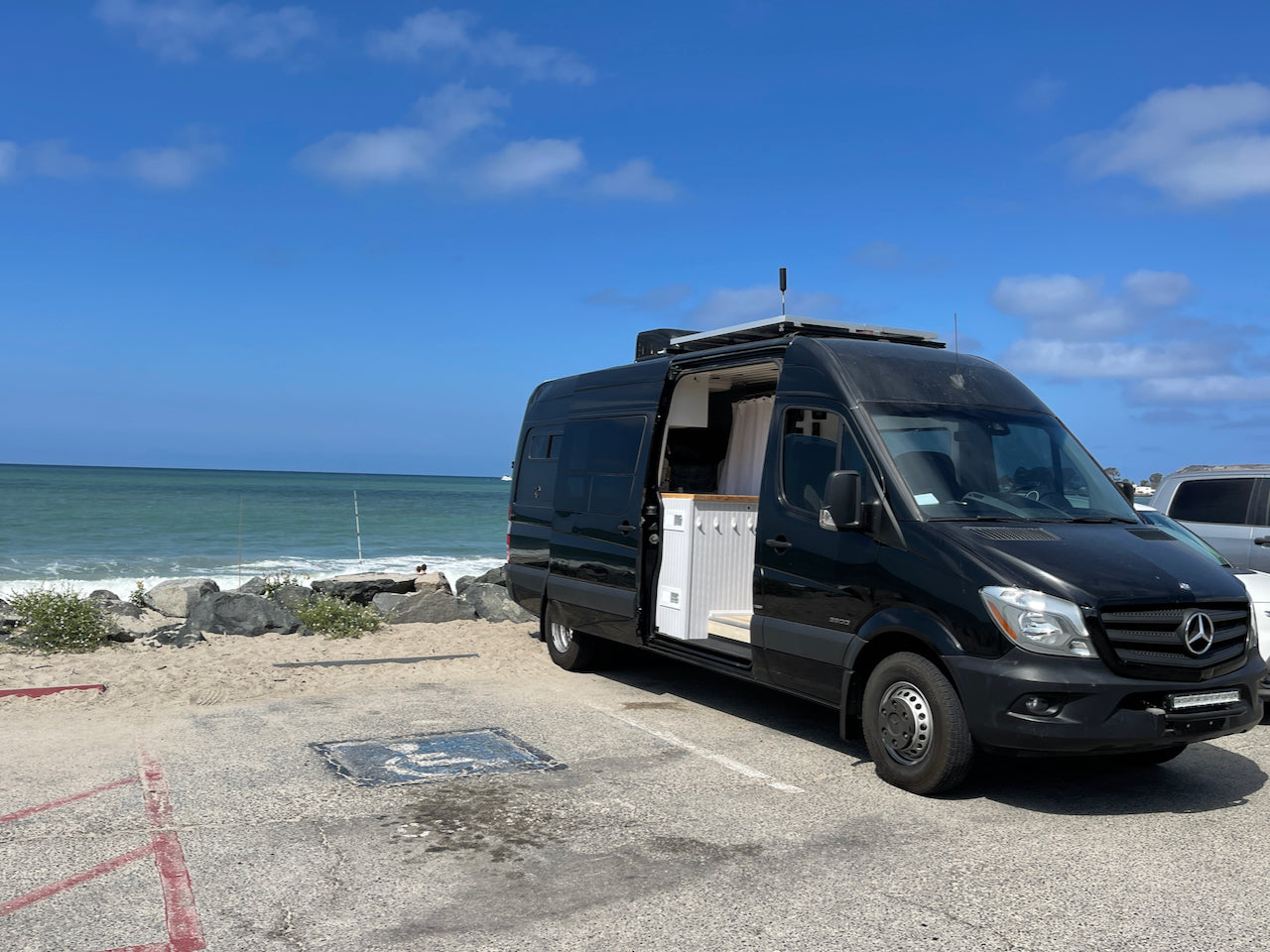 Black Mercedes Sprinter **rv rental** parked oceanside.