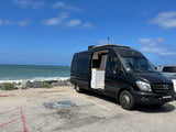Black Mercedes Sprinter **rv rental** parked oceanside.