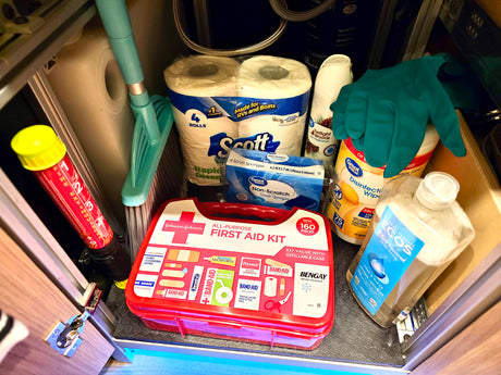 Compact RV rental storage: first aid kit, fire extinguisher, cleaning supplies, and RV-specific toilet paper for travel.