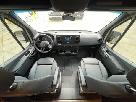 Get ready for your RV rental trip! This spacious van's driver's cabin shows the dashboard, steering wheel, and front seats.