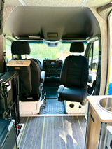 Inside an rv rental: View of a custom camper van interior with front seats, custom floor, & kitchenette.