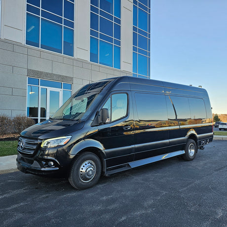 This elegant black Mercedes-Benz Sprinter van is a fantastic RV rental choice, parked in front of a sleek blue-windowed building.