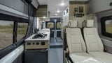 View of an RV rental interior: compact kitchen, two passenger seats, and control panels. Ready for adventure.