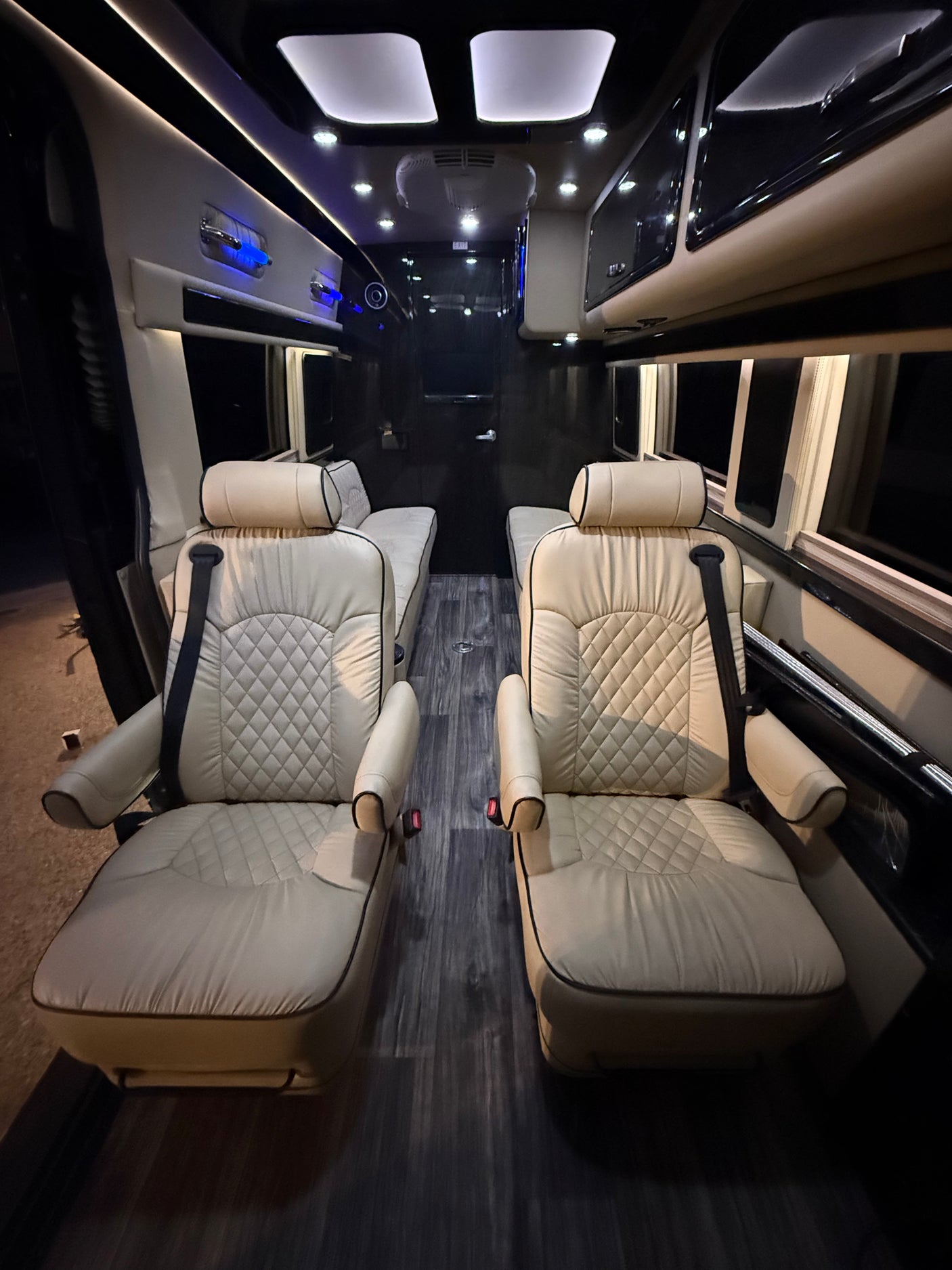 Luxury RV rental interior with cream quilted seats, dark wood floor, and ambient lighting. Perfect for comfortable travel.