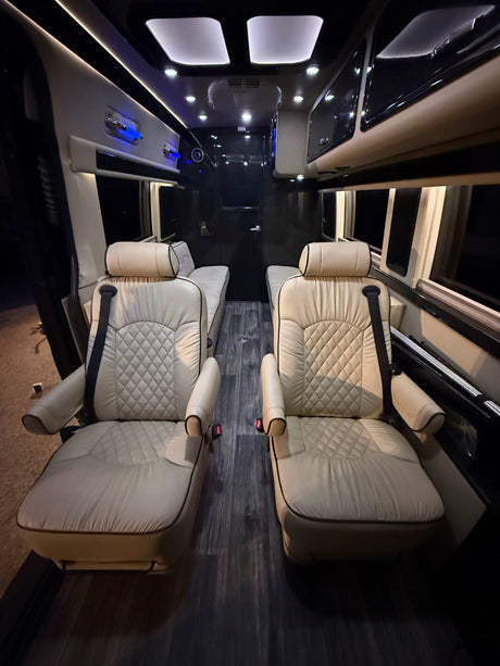 Luxury RV rental interior with cream quilted seats, dark wood floor, and ambient lighting. Perfect for comfortable travel.