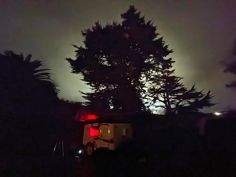 Night scene: RV rental illuminated by red lights under moonlit trees. Perfect for camping adventures.
