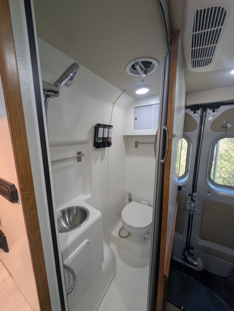 This RV rental features a compact wet bath with shower, toilet, and sink, designed for comfort in your camper.