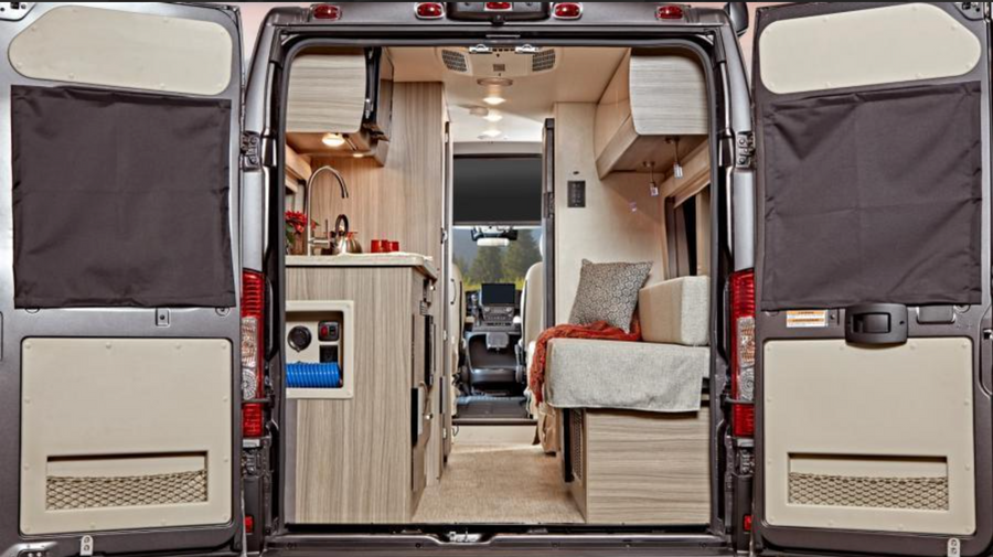 View from rear: an RV rental's inviting interior. Left: functional kitchen. Right: comfortable seating/bed. Doors open to reveal.