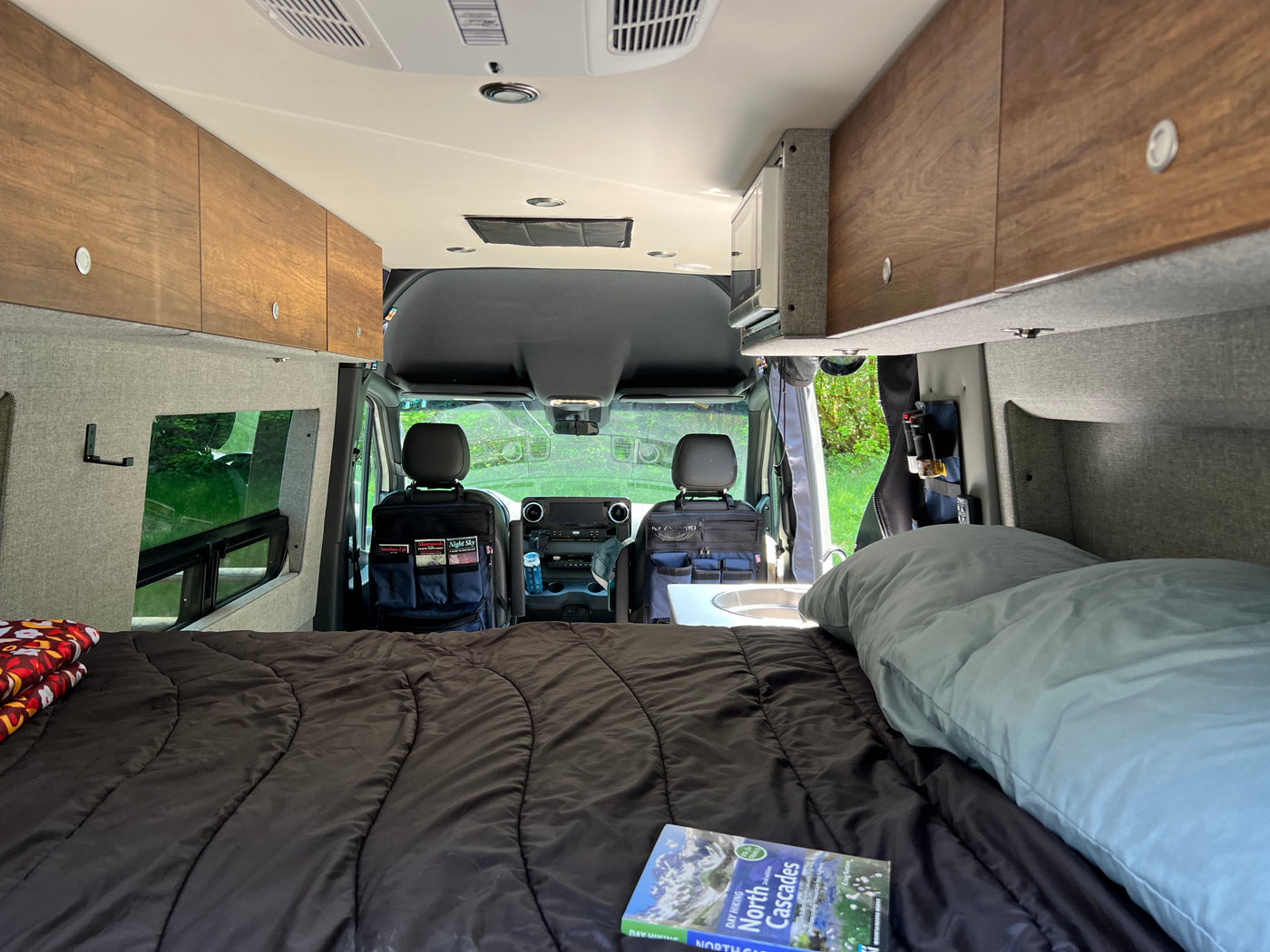 Inside an RV rental: a comfortable bed, compact kitchen area, and ample storage, ready for exploring the scenic outdoors. — photo 19