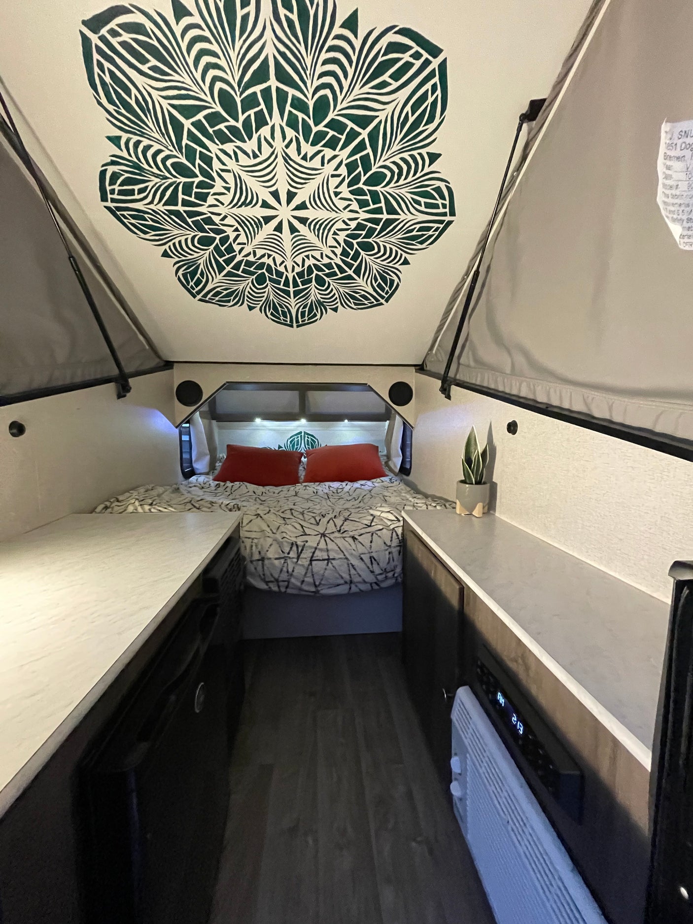 Cozy A-frame RV rental interior with a unique ceiling design, bed, and compact living space. Ideal for your next adventure.