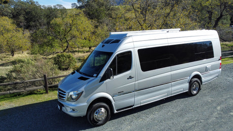 This silver Sprinter RV rental is ready for adventure, parked in a scenic natural setting.