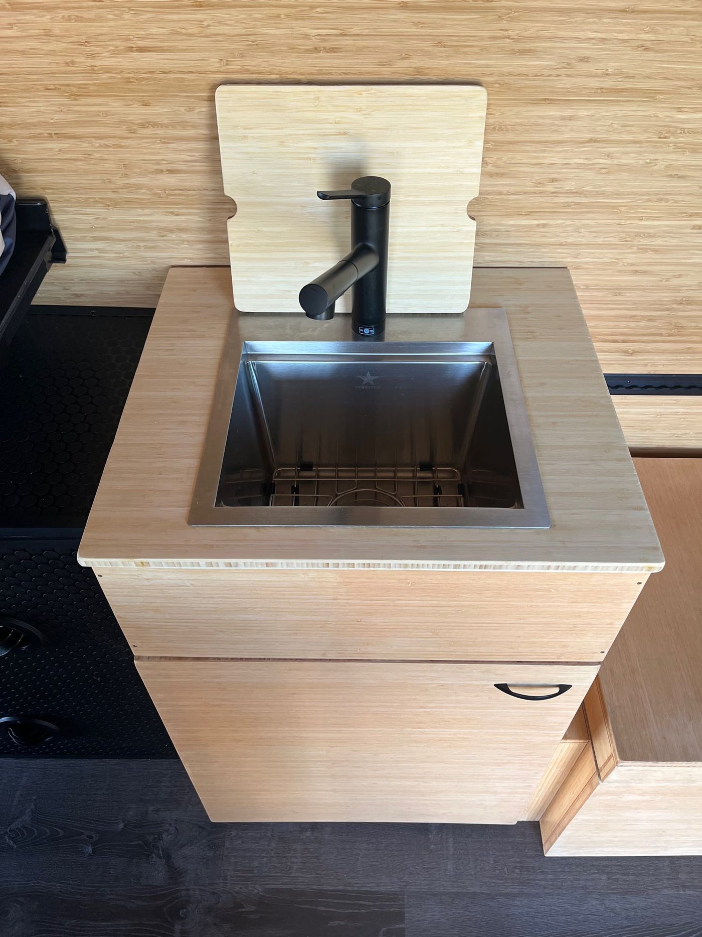 Stylish RV rental compact kitchen: bamboo wood interior, stainless steel sink, black faucet, and custom cutting board. — photo 11