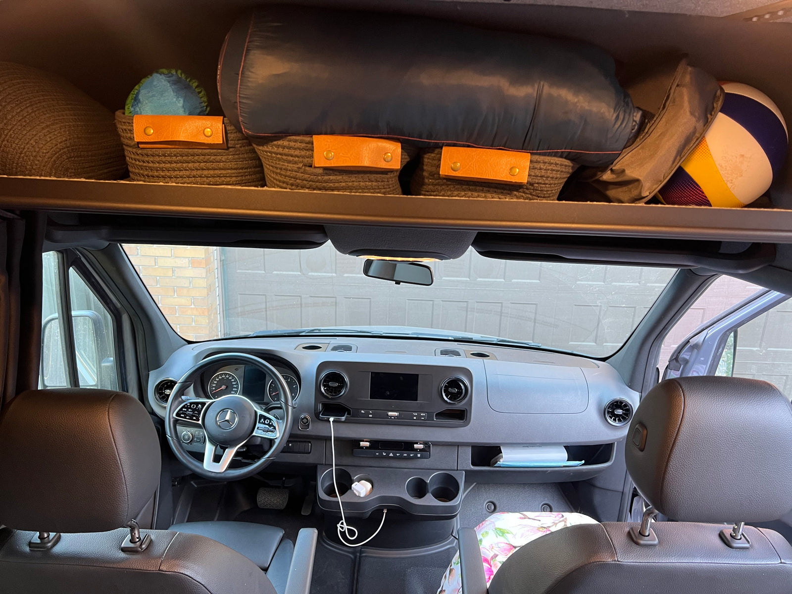RV rental interior: Mercedes van cabin with dashboard, phone charging, & organized overhead storage for gear and baskets.