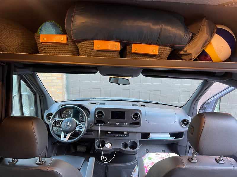 RV rental interior: Mercedes van cabin with dashboard, phone charging, & organized overhead storage for gear and baskets. — photo 9
