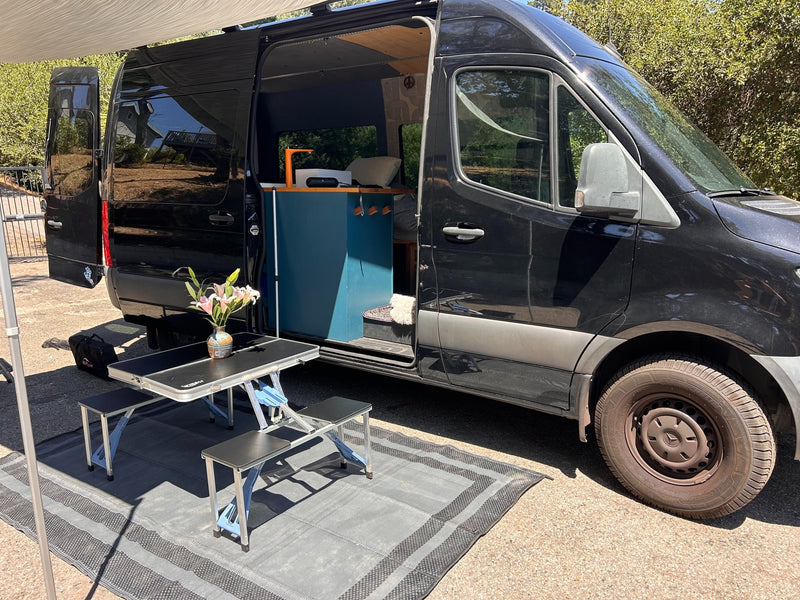  enjoying an outdoor picnic setup with a portable table and flowers.|Black RV rental — photo 4