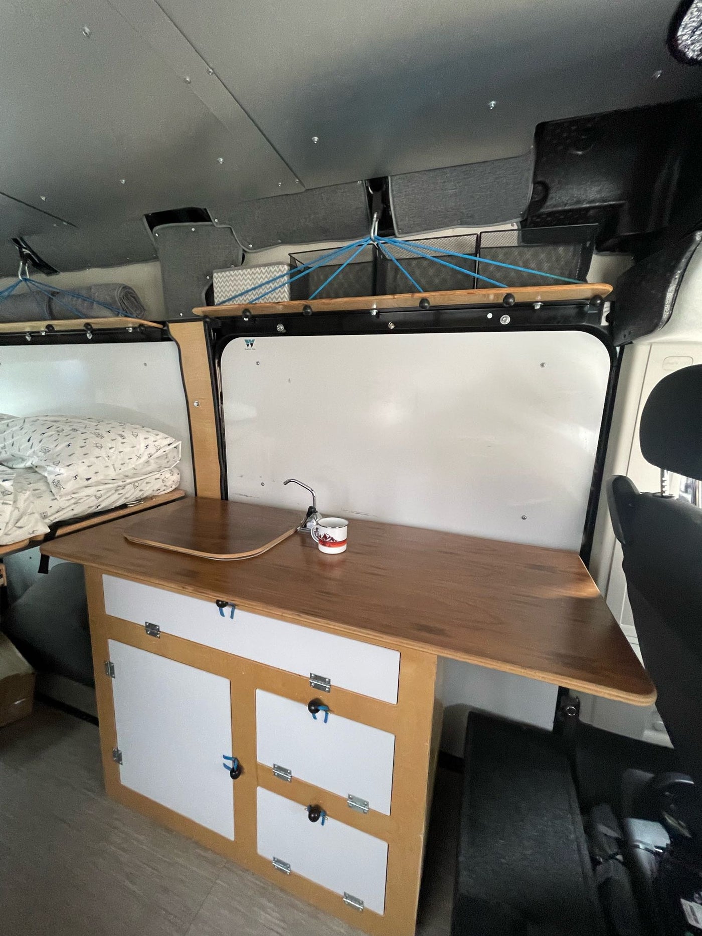  and 'Happy Camper' mug visible.|RV rental: Inside this black camper van — photo 14