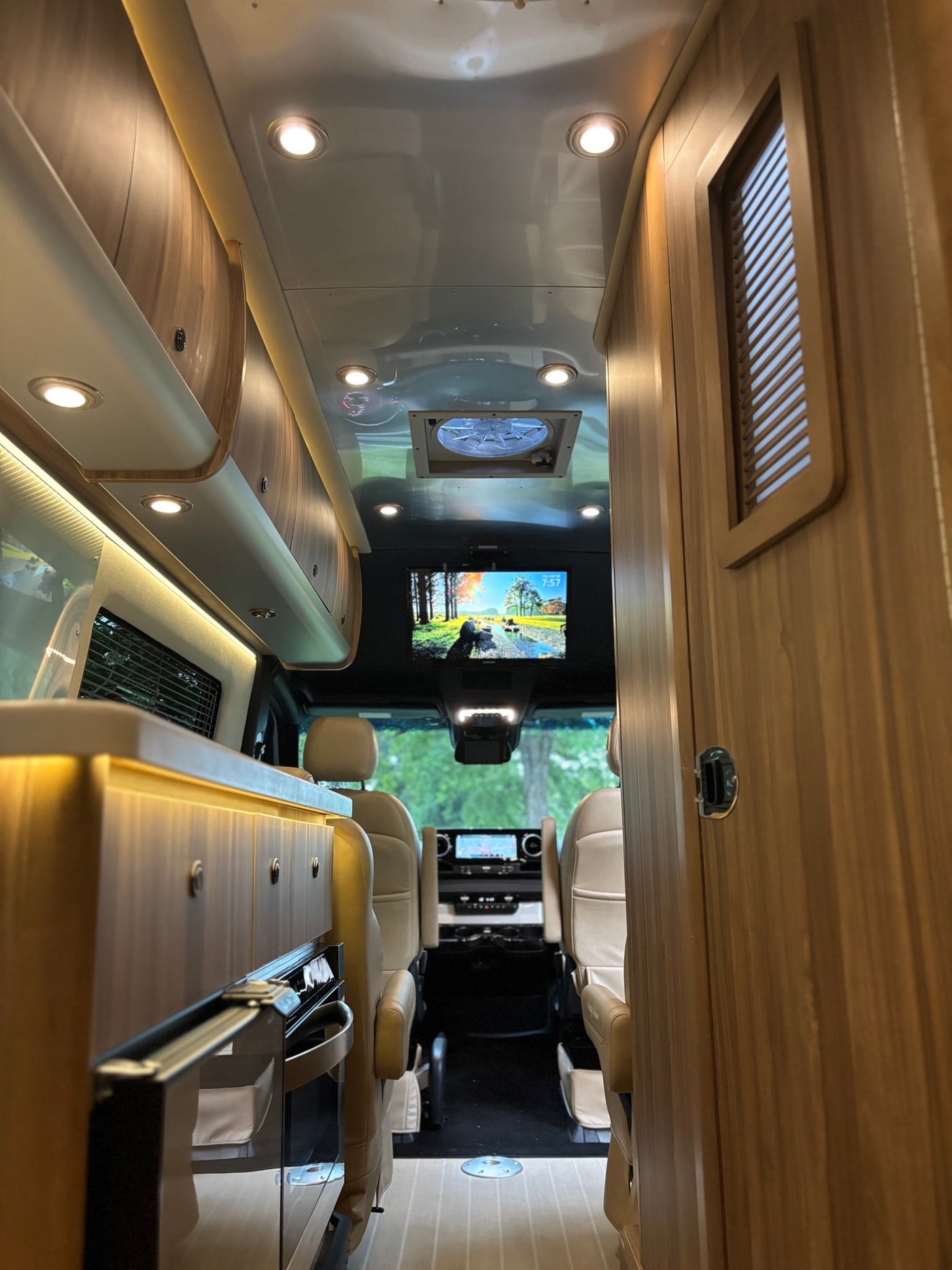 parked on lush green grass.|Step into this luxurious RV rental: a well-appointed interior with a kitchenette — photo 3