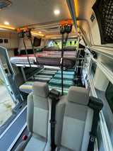 An RV rental van interior features a double bunk bed system with vibrant blankets, along with rear passenger seats, ideal for travel.