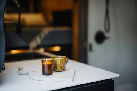 Cozy RV rental interior with a lit candle and a warm drink on a counter, perfect for relaxing moments.