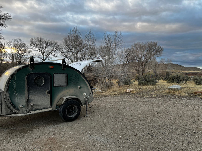 and storage. Night camp scene with snowy mountains.|Dusty green teardrop RV rental at a campsite with bare trees and a vibrant sunset behind mountains. Perfect for off-grid camping!|This rugged green teardrop RV rental is set against a vibrant sunset sky and mountains — photo 13