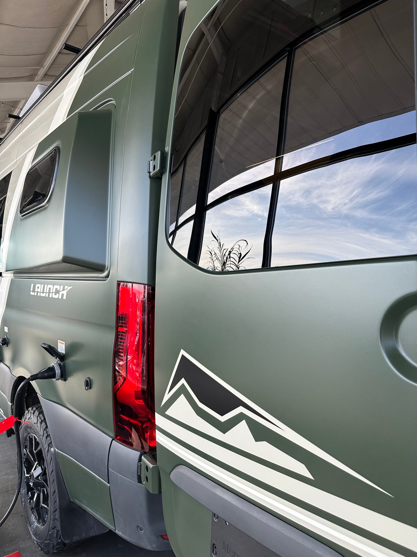 This green "LAUNCH" camper van is hooked up, ready for your next RV rental adventure. A mountain graphic adorns the side.