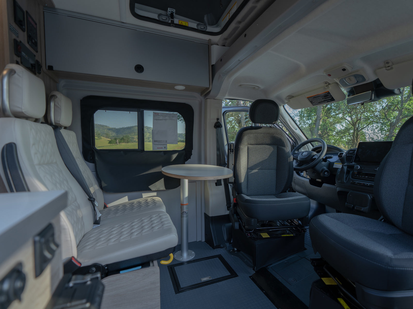 Interior of an rv rental, showcasing versatile seating, removable table, and the driver's cockpit.