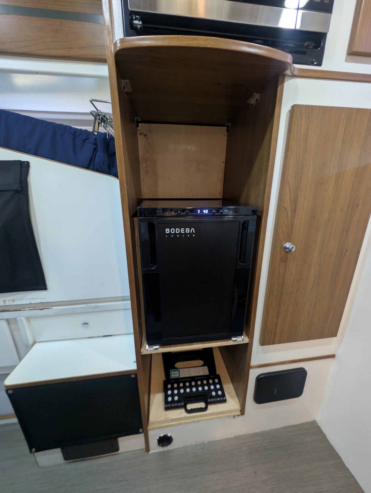 Rv rental interior: Bodega cooler, microwave, and storage unit. A compact setup ideal for mobile living.