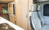 Spacious RV rental interior with modern kitchen, versatile seating, and clever fold-away bed system for comfortable travel.