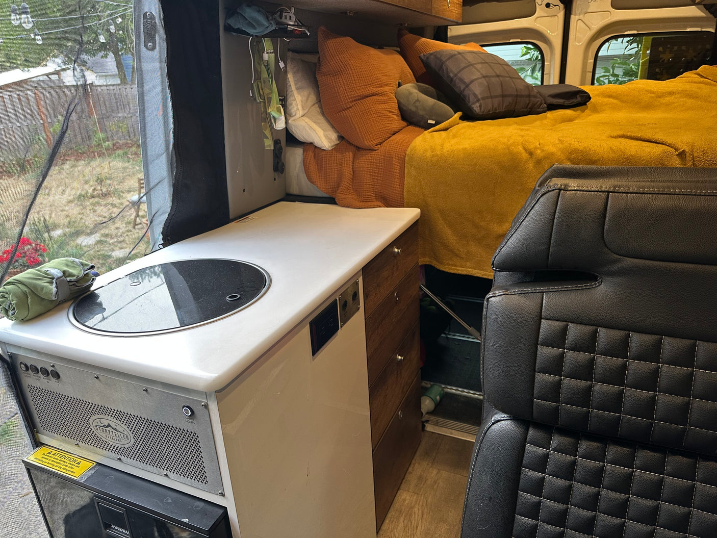 Spacious RV rental interior featuring a compact kitchen, cozy bed, and scenic views for comfortable road trips.