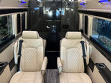 RV rental's luxurious interior with quilted cream leather seats, entertainment display, and sleek wood finishes.