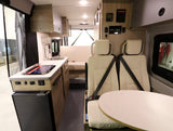 Inside an RV rental, discover a compact kitchen with a sink, stovetop, and fridge, plus versatile seating for travel comfort.