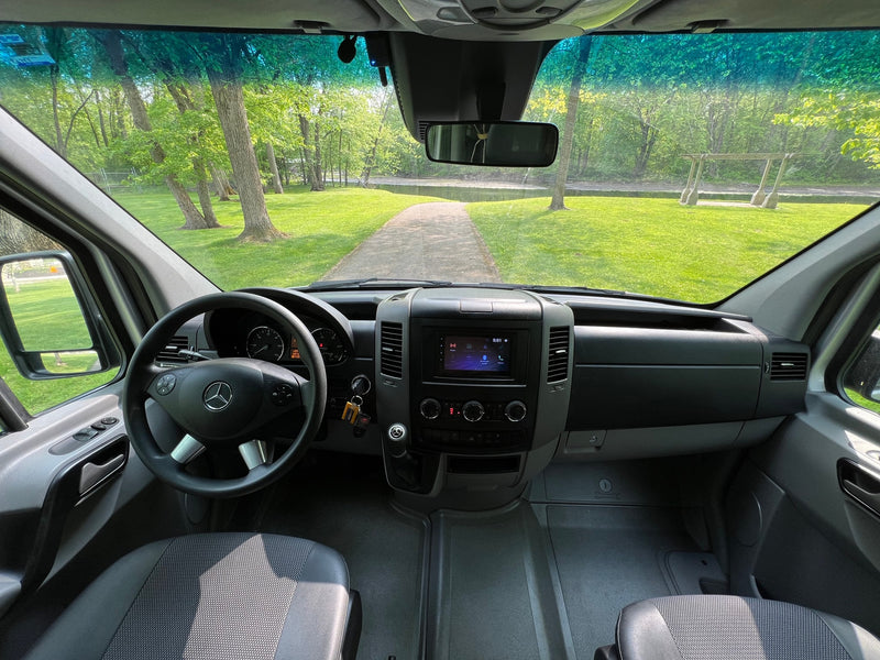 Inside a spacious RV rental, a clear view of a scenic park path with green trees and grass awaits your adventure. — photo 19