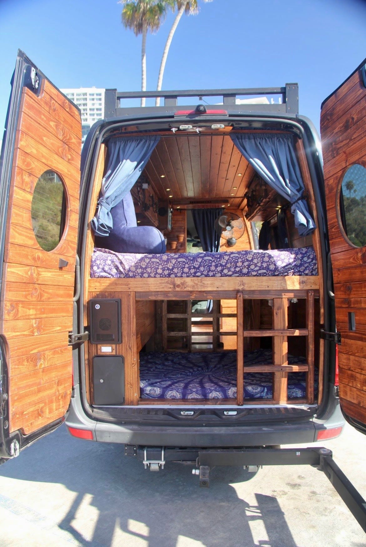  ready for adventure.|A sleek black custom Sprinter van RV rental with open door revealing warm wooden interior. Equipped for road trip adventures by the beach.|Cozy wood-paneled rv rental: full kitchen with colorful tiles — photo 3