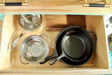 Efficient RV rental kitchen storage: Calphalon pot, colander, and Lodge cast iron skillets neatly organized in a wooden drawer.