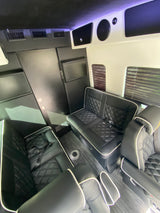 Spacious luxury RV rental interior: black leather seating, entertainment screens, and climate control for ultimate travel comfort.