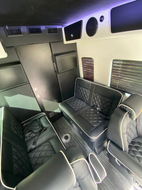 Spacious luxury RV rental interior: black leather seating, entertainment screens, and climate control for ultimate travel comfort.