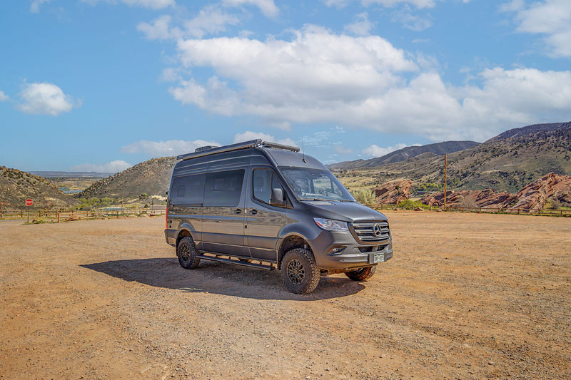 Explore the outdoors! This off-road ready gray rv rental van is parked on a dirt lot amidst scenic mountains. — photo 10