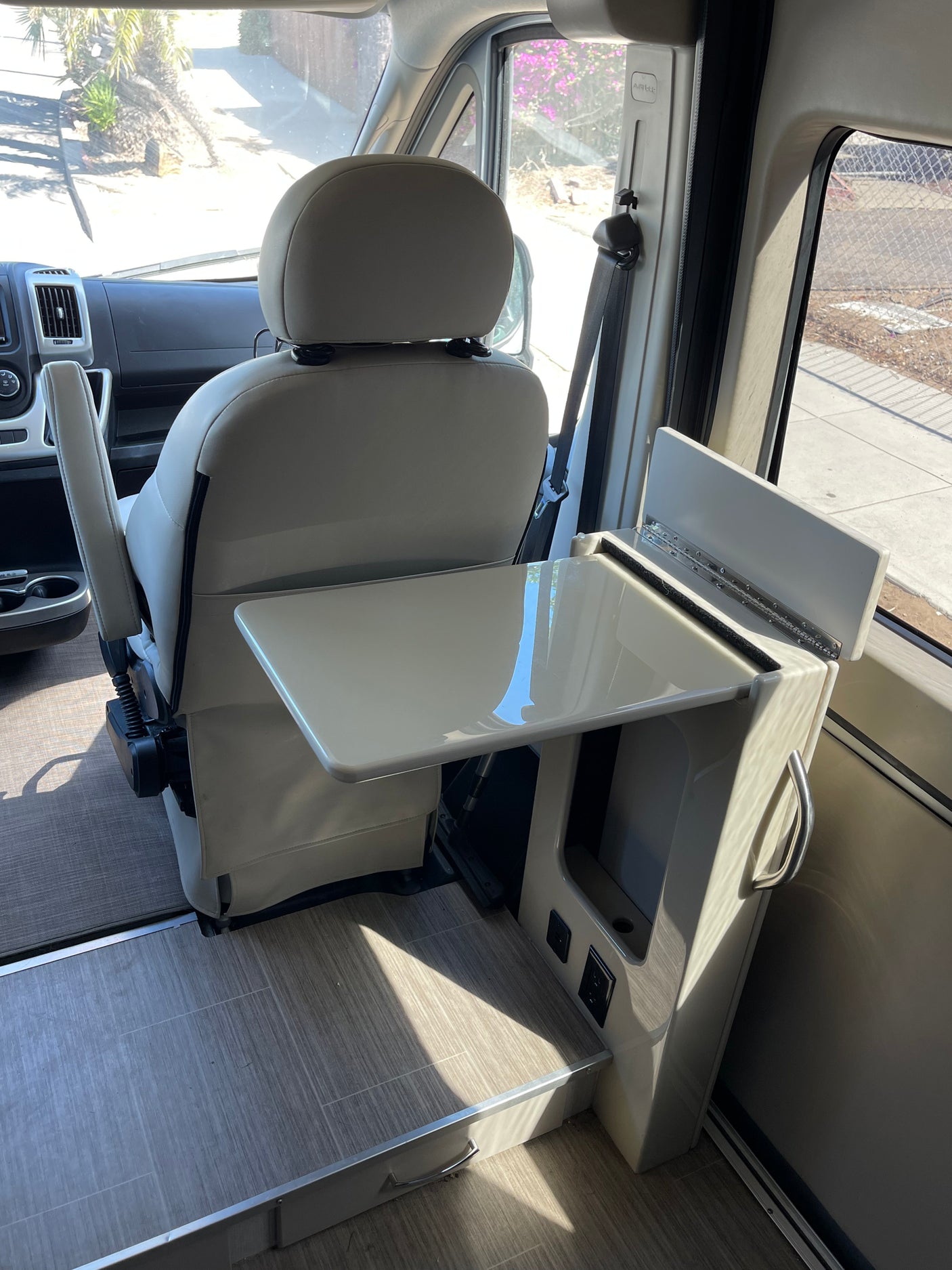 An rv rental's interior: passenger seat swiveled to face a compact table and side console with power outlets for convenience.