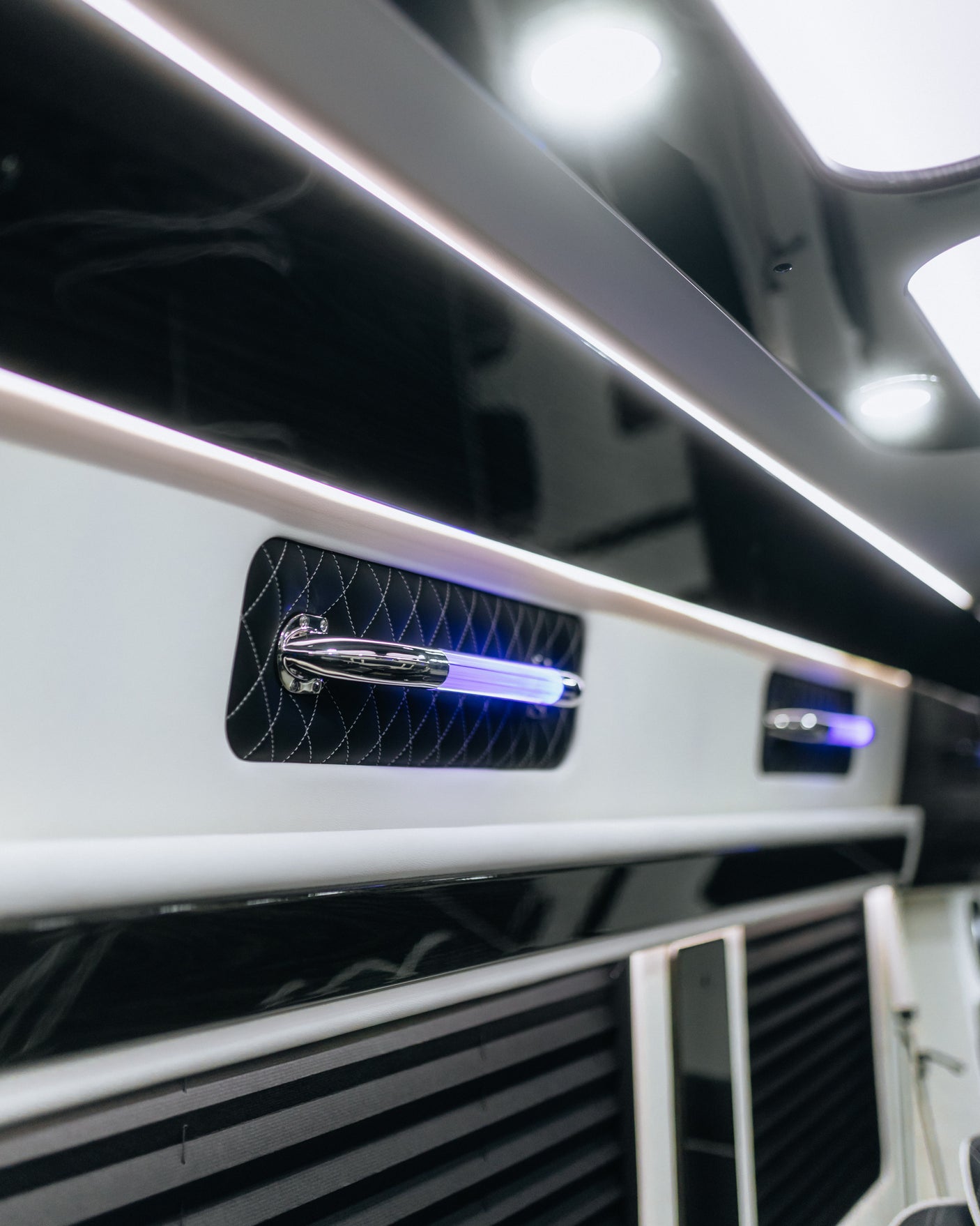 Luxury RV rental interior with modern black & white design, ambient LED strips, and striking blue light feature on quilted panel.