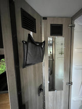RV rental interior features light wood walls, a mesh storage bag, ventilation grates, and a mirrored door to the bathroom.