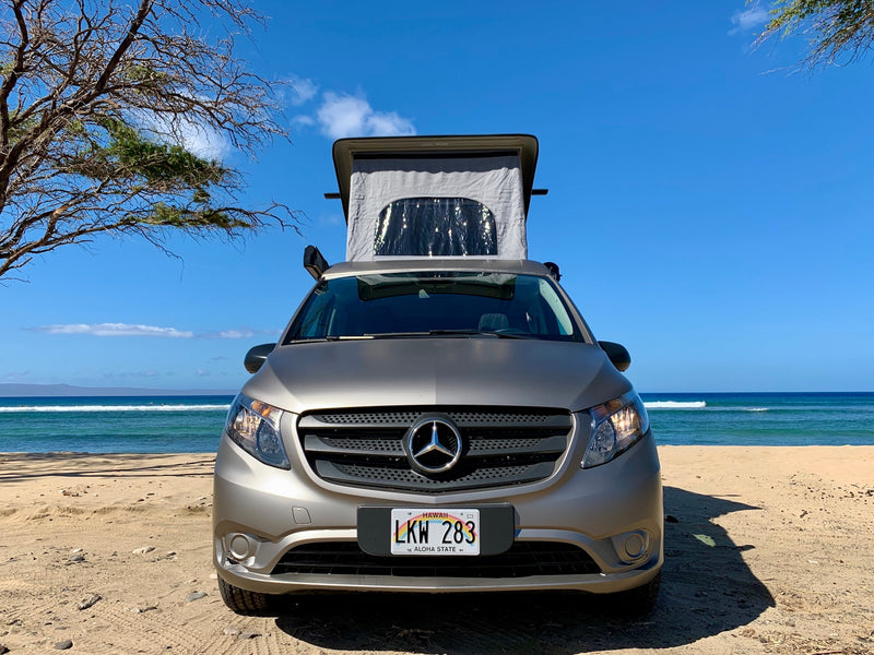 and lush tropical views through its large windows.|Gray camper van RV rental parked on a sandy beach with its awning extended towards the ocean. Ideal for beach camping & travel.|A light grey Mercedes Metris camper van — photo 6