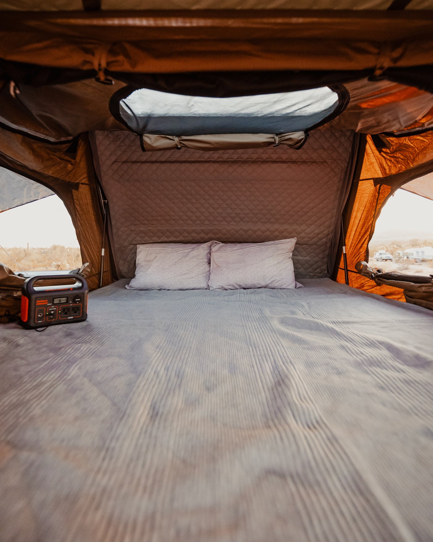 Cozy RV rental sleeping area with a comfortable bed and portable power station, offering desert views.