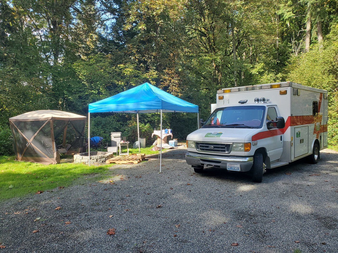 Outdoorsy RV rental, a converted ambulance, with tents and fire pit at a campsite.