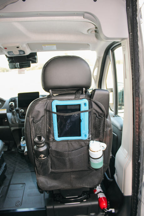 RV rental interior: Seat-back organizer holds tablet, bottles, and a fire extinguisher for efficient travel storage.