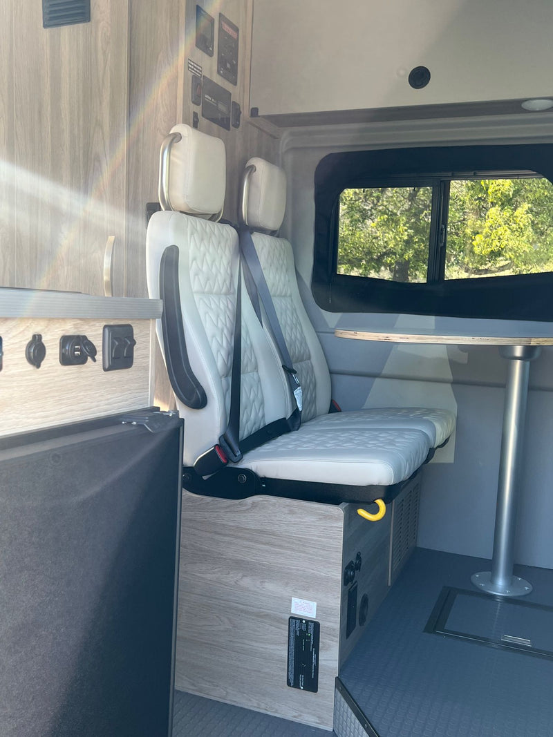  looking out at a sunny road with green trees.|Inside a modern RV rental: compact kitchen with sink — photo 9
