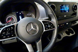 Inside your RV rental: Driver's cockpit of a Mercedes-Benz Sprinter, featuring a modern dashboard, steering wheel, and infotainment system.