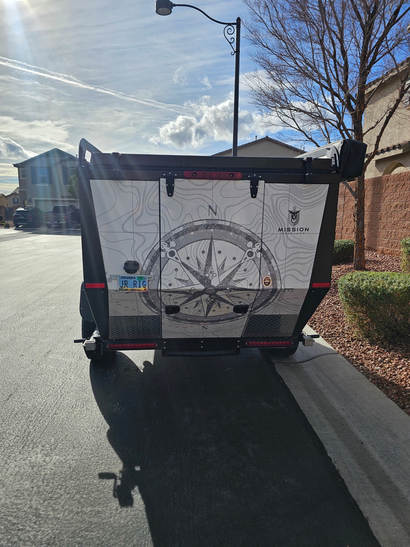 Rear of a custom Mission Overland trailer with compass wrap & Nevada 'JR RIG' plate. An impressive choice for your RV rental adventure.
