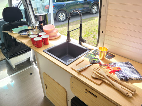 This RV rental features a well-equipped compact kitchen with a sink, cookware, and dishes for your travel needs.