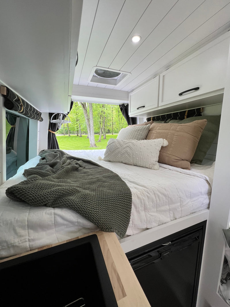 Cozy RV rental bedroom featuring a comfy bed with plush pillows, modern cabinets, and a beautiful nature view. — photo 4