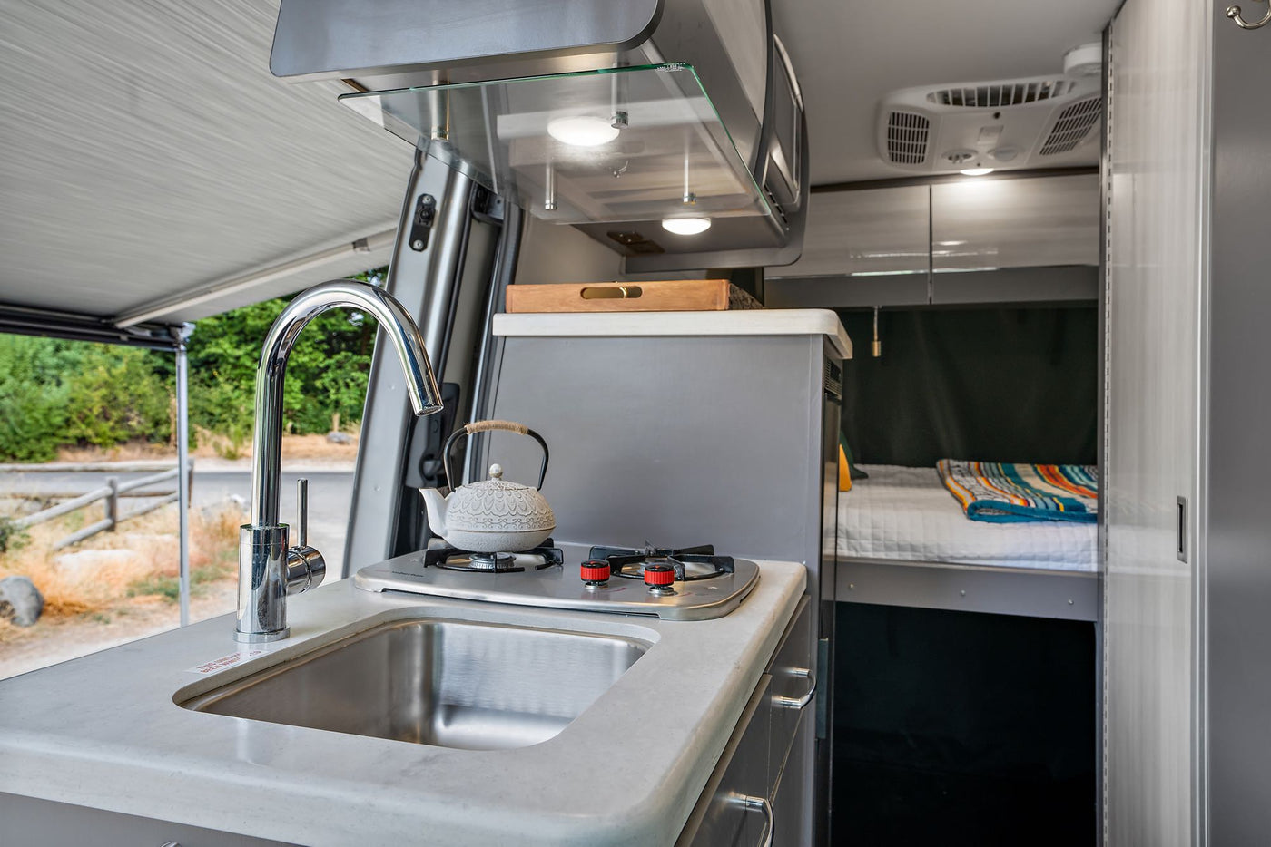  revealing the interior. Chairs & a cooler are set up outside.|Silver Sprinter camper van rv rental with open doors — photo 4